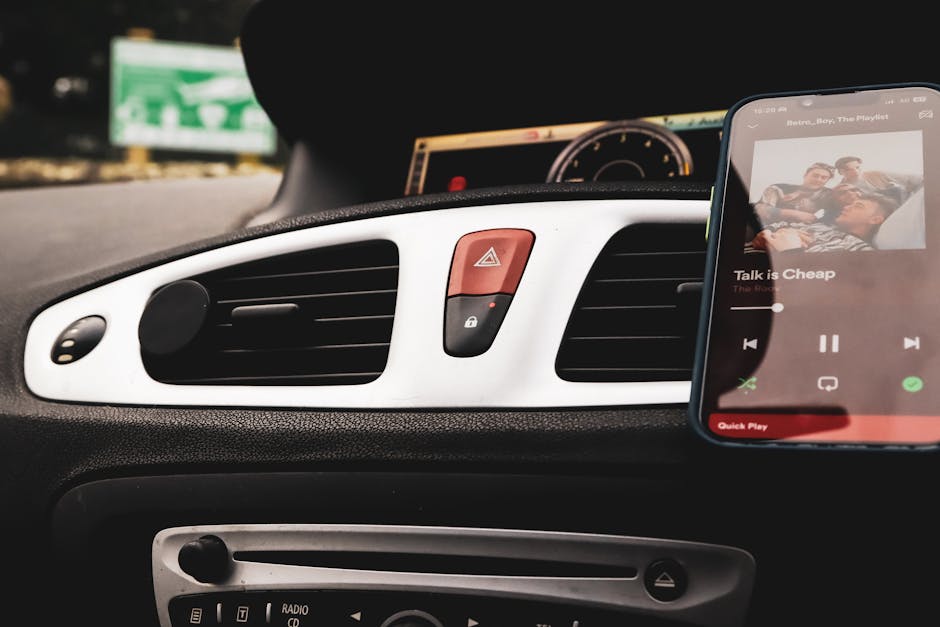 Car interior with smartphone on Spotify and dashboard controls in focus.